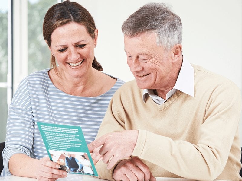A resident man sitting next to a woman discusses something over literature.