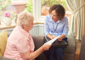 A resident and housing officer wearing a lanyard discuss a paper document that they're holding between them.