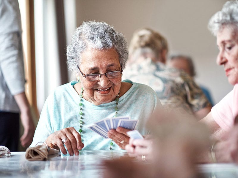 A resident plays cards and smiles alongside a friend.