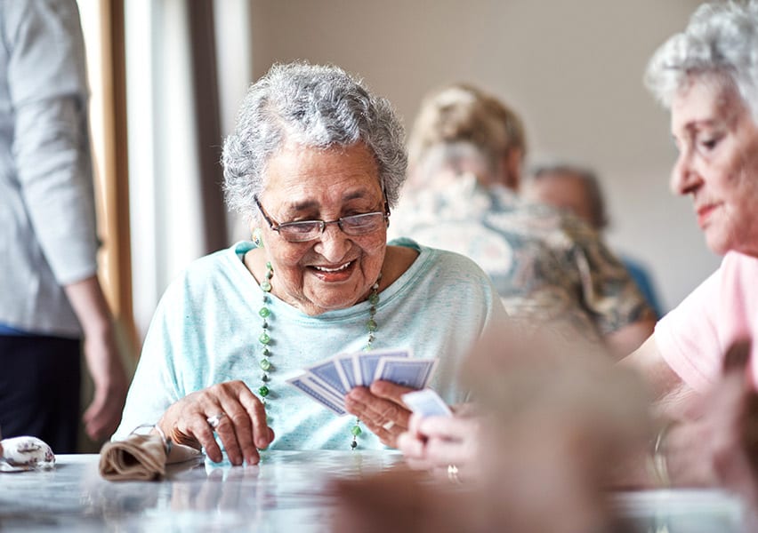 A resident plays cards and smiles alongside a friend.