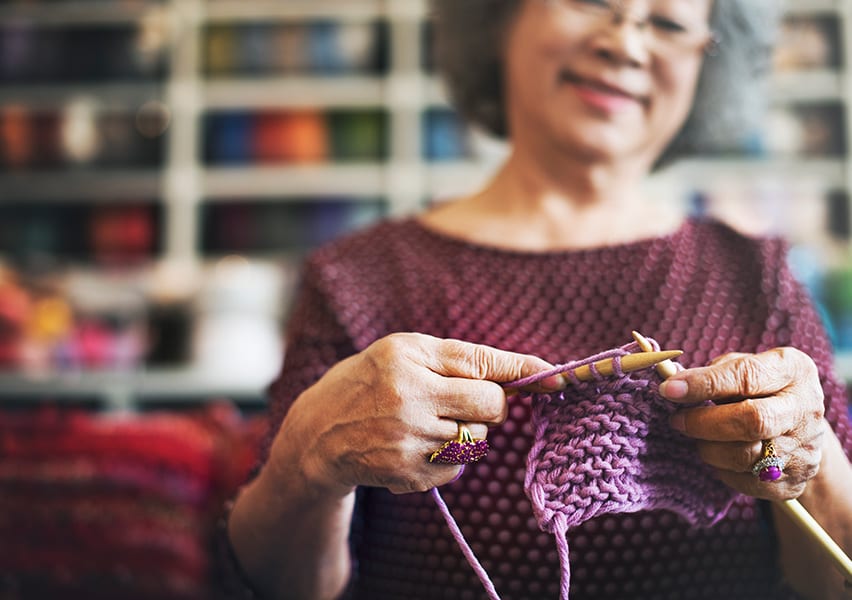 A senior resident looks happy and content as she knits while sitting in a room meant for pursuing hobbies.