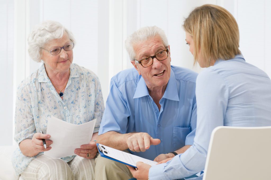 A senior couple discuss items with their healthcare advocate