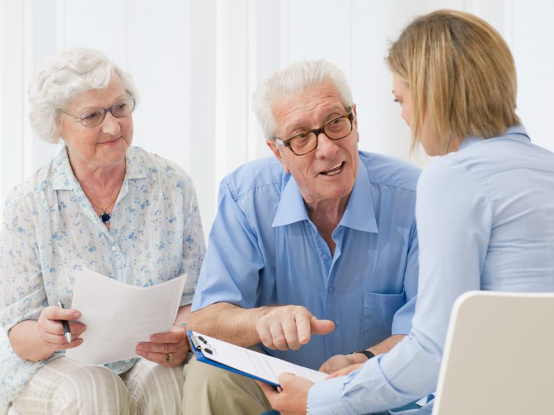 A senior couple discuss items with their healthcare advocate