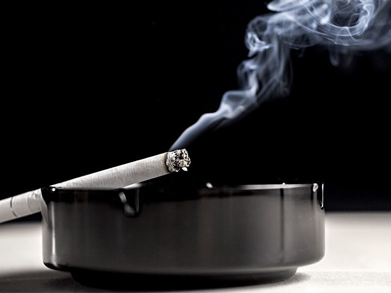 A cigarette smolders in an ashtray representing the health risks of smoking over age 50