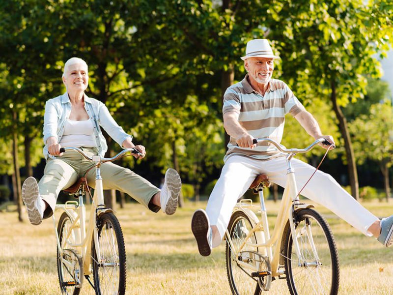 An aging couple rides bicycles together in the park