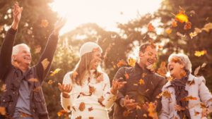 Two couples enjoy playing in and observing the changing leaves, which is on our list as one of the best fall activities for seniors.