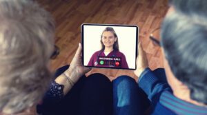 An elderly couple uses a tablet to video chat with their doctor